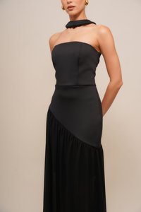 Black evening dress with a strapless bodice and asymmetrical layered skirt. Made from smooth fabric, featuring a flowing, gathered texture.