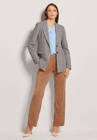 Karo-Blazer in Grau und Creme, kombiniert mit einer hellblauen Bluse und braunen Cordhosen. Besitzt eine taillierte Passform und strukturierte Revers.
