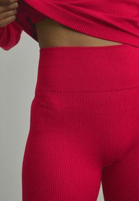 Geribbelde roze legging met een hoge tailleband, met een gestructureerd oppervlak en een strakke pasvorm rond de taille en heupen.