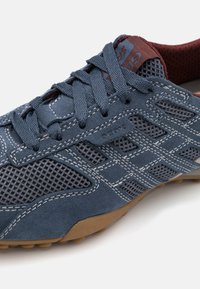 Sötétkék sportcipő, amely velúr és hálós anyagok keverékéből készült, kontrasztos varrással és gumitalppal. Geox logó látható az oldalon.