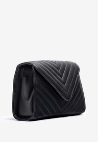Zwarte gewatteerde leren clutch met een opgevouwen klep, met een visgraatpatroon en een gladde textuur. Rechthoekige vorm met een stevige basis.
