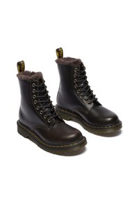 Botines de cuero negro con forro de piel sintética marrón, diseño de cordones, costuras amarillas características y suela de goma texturizada.