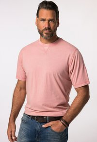 T-shirt rosa in cotone a maniche corte con collo a giro, vestibilità rilassata e cuciture a vista, abbinato a jeans in denim blu.