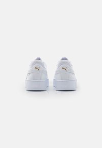 Pair of white Puma sneakers with gold logo on heel, shown from the back against a plain white background.