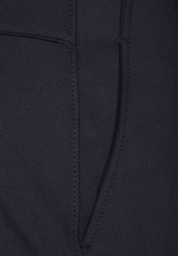 Mörkblått tyg med en slät struktur, med stygn och en fickdesign. Tydliga linjer med en enkel, funktionell form.