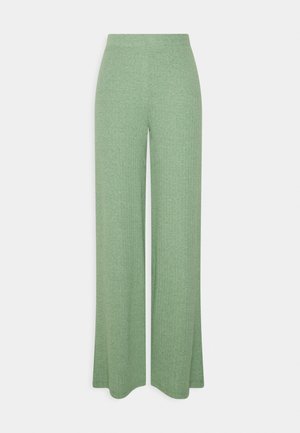 Pantaloni larghi a coste verdi con una texture morbida e una vita elastica, caratterizzati da un taglio dritto e una silhouette fluida.