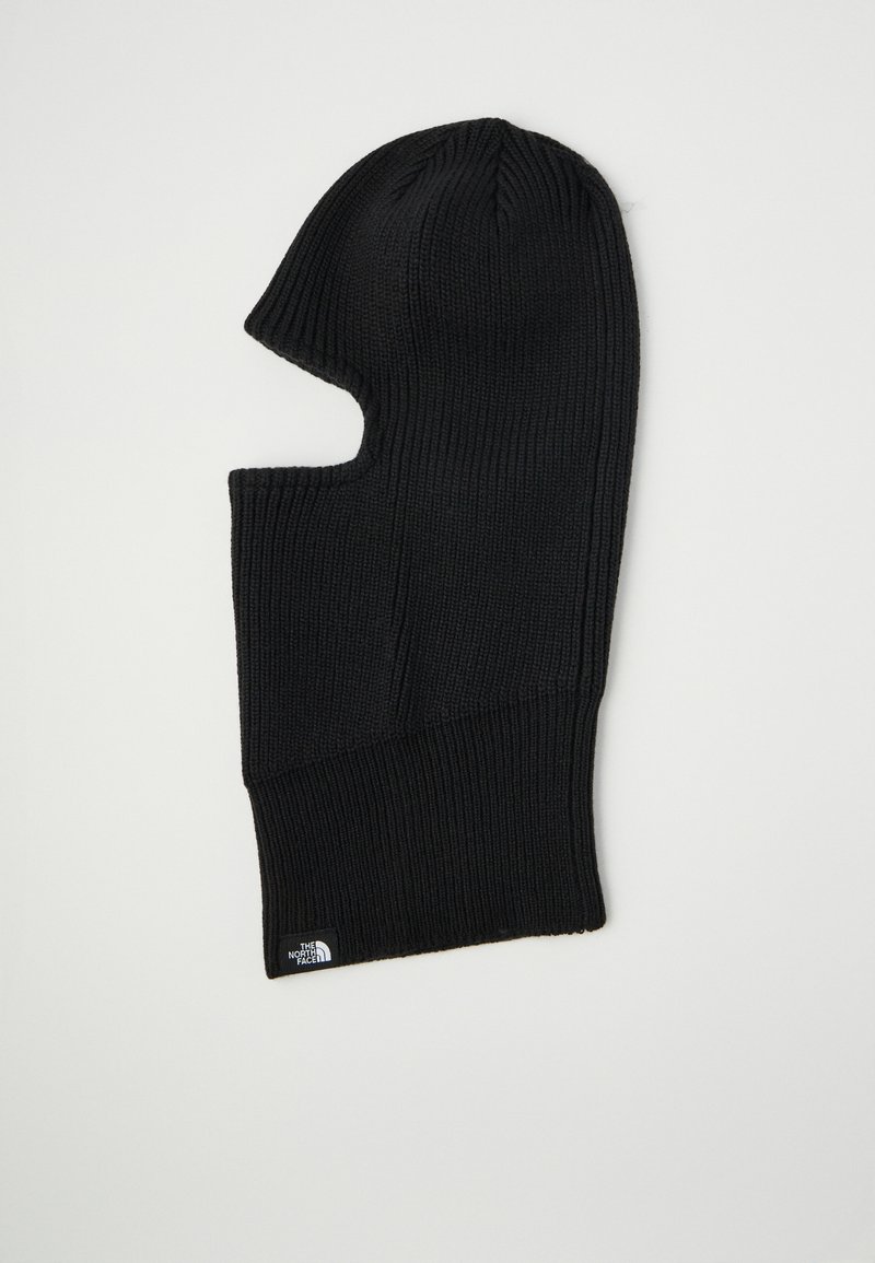 Melnā adīta balaclava ar noapaļotu augšu, kas nodrošina pilnīgu sejas segumu un ir ar atvērumiem acīm un mutei. Iespējots neliels logotipa tags.