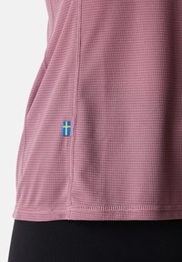 Korte mouwen, lichtpaars sportshirt met een gestructureerd patroon. Bevat een blauw-en-geel Zweeds vlaglabel nabij de zoom en gestikte naden.