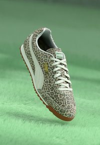 Tenisice s uzorkom leopardove kože sa bežom tkaninom, bijelim akcentima, sistemom vezivanja i đonom od gume. Imaju zeleni logo i podstavljeni okovratnik.