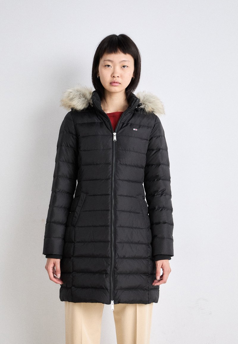 Must sulejope karusnahast ääristusega kapuutsiga, esikinnis tõmblukuga, soonikkoes varrukate ja küljetaskutega. Omadused hõlmavad tikandmustrit ja põlveni ulatuvat disaini.