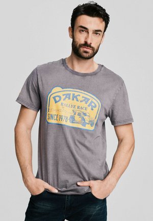 Szara bawełniana koszulka z grafiką Dakar Rally w kolorze żółtym i niebieskim. Okrągły dekolt, krótkie rękawy, postarzany wygląd, luźny krój.