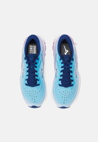 Scarpe da corsa azzurro chiaro con tomaia testurizzata, lacci blu navy e dettagli in contrasto. Presentano una finitura perforata e una suola bianca spessa con evidenti accenti rosa.