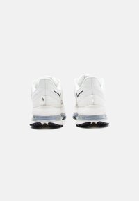 White athletic shoes with mesh upper, padded collar, and visible air unit in the sole. Features black accents and textured rubber outsole.