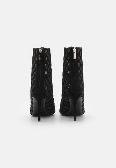 Botine negre cu toc înalt, cu un design texturat împletit și închidere cu fermoar la spate. Prezintă un material din suede și un vârf ascuțit elegant.