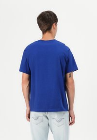 T-shirt di cotone blu reale con collo rotondo e maniche corte. Texture liscia con vestibilità comoda, abbinato a denim chiaro.