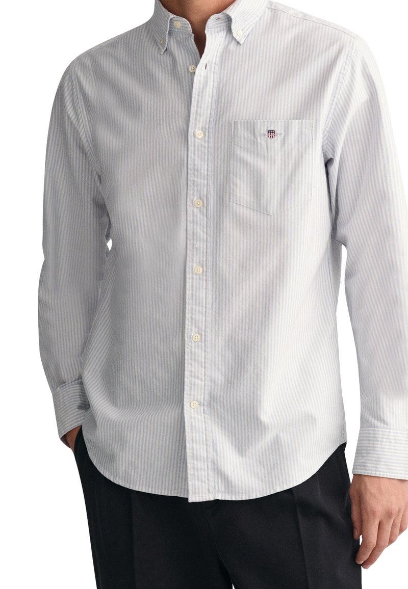 Lange mouw button-down shirt in lichtblauw en witte strepen. Voorzien van een borstzak en een rechte kraag. Gemaakt van een katoenmix.