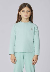 Maglia a maniche lunghe verde menta in tessuto morbido, con scollo rotondo e piccolo logo sul petto a sinistra. Abbinata a pantaloni coordinati.