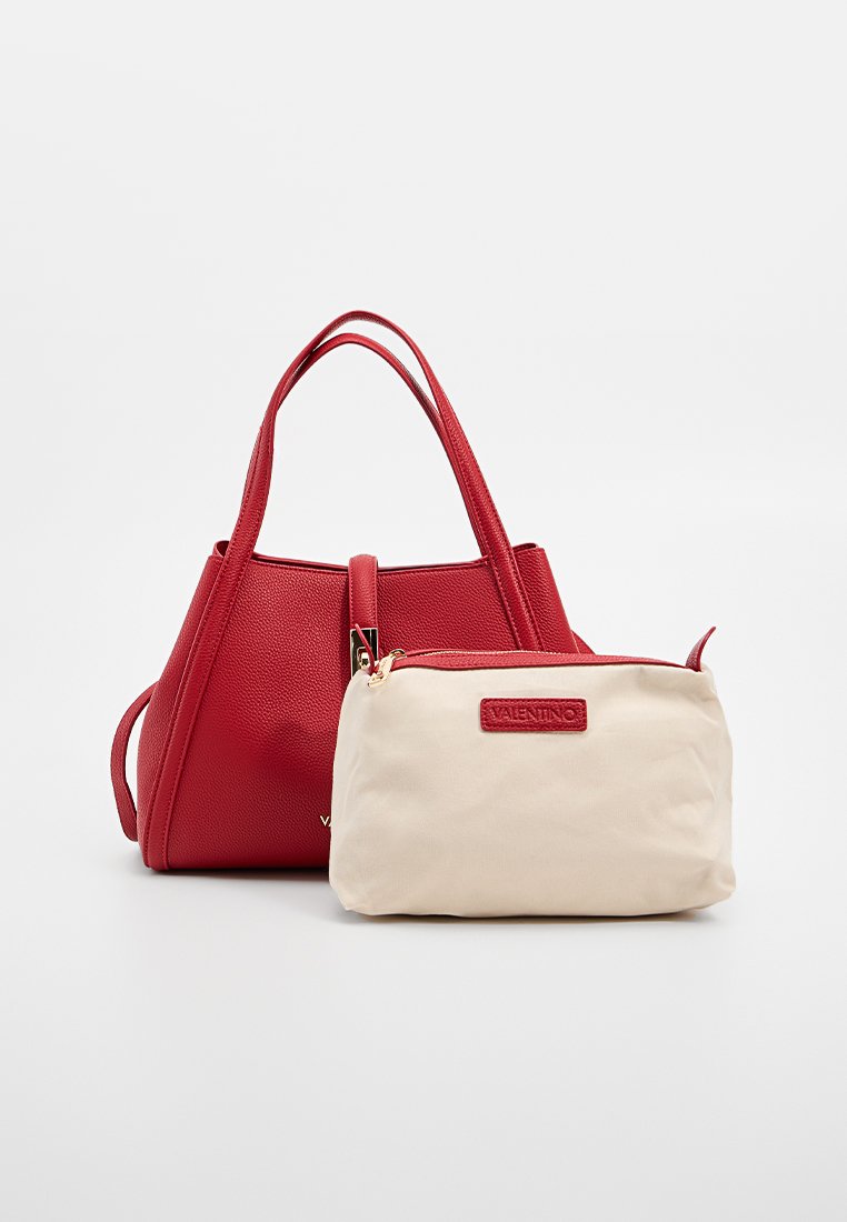 Sac fourre-tout en cuir texturé rouge avec des anses lisses et une pochette en tissu beige, arborant un patch logo rouge et une fermeture éclair.