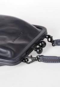 Borsa in pelle blu navy con una texture liscia, dotata di una struttura rigida, hardware in metallo e una tracolla staccabile con chiusura a clip.