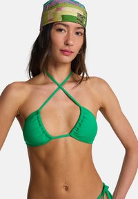 Πράσινο τοπ μπικίνι με λεία υφή, ρυθμιζόμενες πτυχώσεις και λεπτούς σταυρωτούς ιμάντες. Διαθέτει μινιμαλιστικό τρίγωνο σχήμα και εφαρμοστή σχεδίαση.