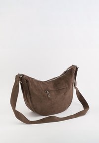 Brun ruskinds skuldertaske med en buet form, lynlåslomme, forlommesrum og en bred stofrem. Glat tekstur.