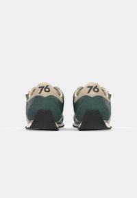Scarpe da ginnastica verdi e beige con un motivo testurizzato, caratterizzate da accenti neri e dal numero "76" sul tallone. Suola in gomma progettata per la trazione.
