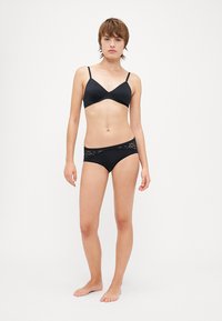 Black lingerie set featuring a smooth bralette with thin straps and lace-accented hipster panties. Simple, minimalistic design, and soft texture.