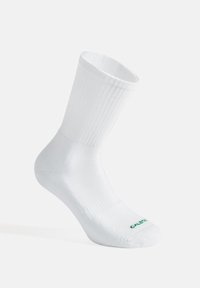 Calzino bianco in cotone con design a costine, lunghezza a metà polpaccio, e un logo verde sulla punta. Texture liscia con una forma sagomata.