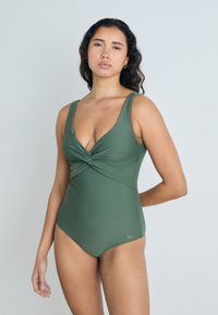 Μοντέρνο ολόσωμο μαγιό σε ελιά, με σχέδιο στροφής στο στήθος, φαρδιές λεπτομέρειες στους ώμους και λείο, ελαστικό ύφασμα.