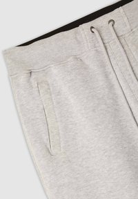 Szare dresy z czarnym elastycznym pasem, z sznurkiem do regulacji i bocznymi kieszeniami. Wykonane z miękkiego, teksturowanego materiału.