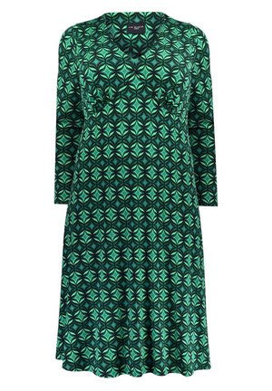 Długa sukienka z długimi rękawami w geometryczny wzór w kolorach zielonym i czarnym, z dekoltem w serek i dopasowanym biustem, lekko rozszerzająca się ku dołowi.