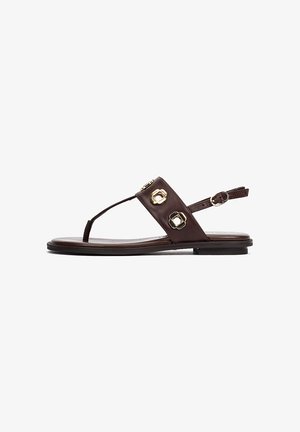 Sandalia plana de cuero marrón oscuro con correa en el tobillo, diseño tipo dedo y dos tachuelas decorativas geométricas doradas en la correa superior.
