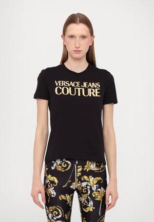 T-shirt en coton noir à manches courtes avec un audacieux logo doré "Versace Jeans Couture" sur la poitrine.