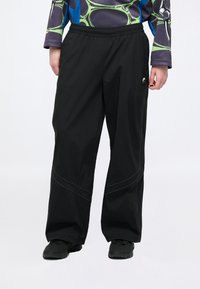 Μαύρο παντελόνι με φαρδιά πόδια και ελαστική μέση, με αντίθετη ραφή και μικρό λογότυπο στο πλάι. Κατασκευασμένο από ελαφρύ υλικό.