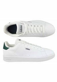 Sneaker Adidas con una toma superiore in sintetico bianco, con un accento verde sul tallone, punta rotonda e suola piatta in gomma, dotate di lacci e dettaglio del logo sulla linguetta.