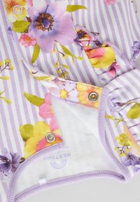 Tissu à motifs floraux présentant des fleurs violettes, jaunes et roses sur un fond rayé lilas, avec des fermetures à pression et des bords doux.