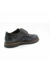 Chaussure habillée en cuir noir avec des détails en brogue, surfaces lisses et texturées, bout rond et semelle plate, avec des accents marron.