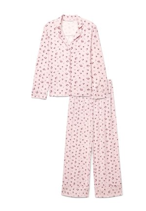 Haut de pyjama à manches longues rose clair avec boutons et pantalon assorti avec un petit motif floral rouge foncé.