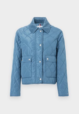 Blauer gesteppter Mantel mit Druckknöpfen, Cordkragen und zwei Vordertaschen auf einem schlichten weißen Hintergrund.