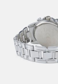 Montre en acier inoxydable argenté avec un bracelet à maillons. Surface lisse et polie avec un cadran circulaire et une couronne.