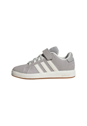 Des baskets en daim grises présentent une sangle Velcro, trois bandes blanches contrastantes et une semelle en caoutchouc avec une semelle extérieure en gomme.