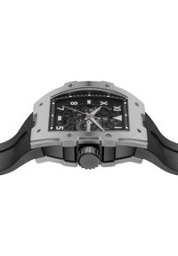 Montre au design squelettique avec un boîtier en acier inoxydable argenté, un bracelet en caoutchouc noir et une couronne proéminente. Présente un cadran noir avec des chiffres romains.