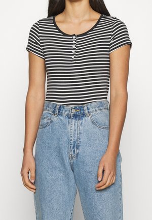 Body en coton à manches courtes, rayé noir et blanc, avec un col rond et une fermeture à cinq boutons, porté avec un jean en denim bleu clair taille haute.