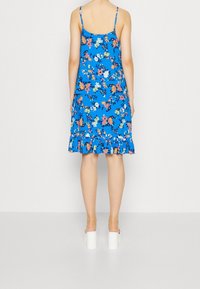 Blue floral dress with spaghetti straps and ruffled hem. Features multi-colored flowers on a solid background, showcasing a lightweight fabric texture.