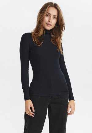 Navy ribbed turtleneck top with long sleeves, fitted design, made from a soft material, paired with black high-waisted jeans.
