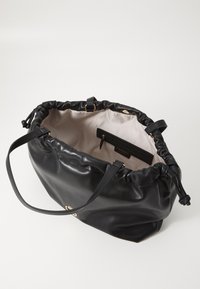 Zwarte leren tote bag met een strakke bovenkant, een gladde structuur, gouden accenten, en een lichte binnenkant met een merklabel.