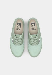 Zapatillas de lona verde menta con diseño de cordones, parte superior texturizada y suela de goma. Presentan el logo de Vans en la plantilla. Superficie suave.