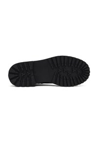 Semelle de chaussure en caoutchouc noir avec un motif texturé, présentant de profonds sillons et des crampons triangulaires pour l'adhérence. Design plat sans talon surélevé.