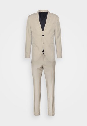 Traje beige con un blazer de un solo botón, botonera negra, solapas en pico y pantalones de corte recto. Tejido suave con un ajuste a medida.