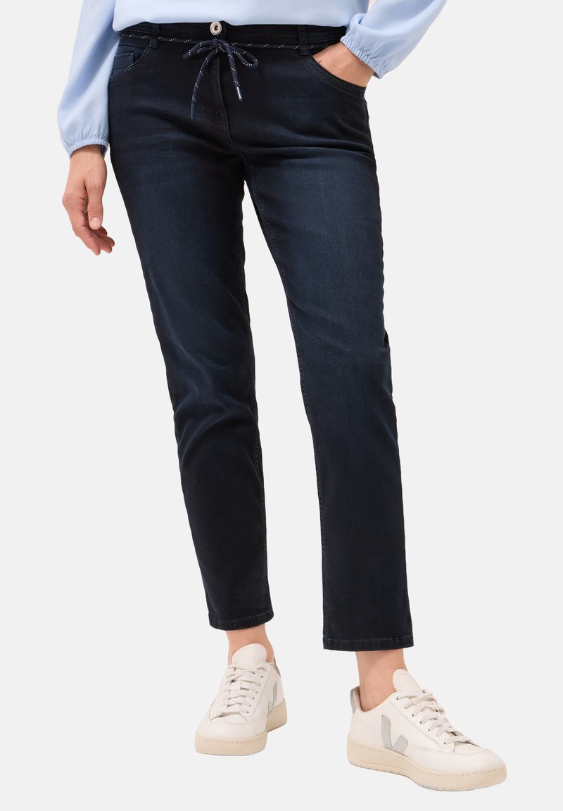Donkerblauwe denim broek met een trekkoord in de taille, zijzakken en een rechte pijp, gecombineerd met witte sneakers.
